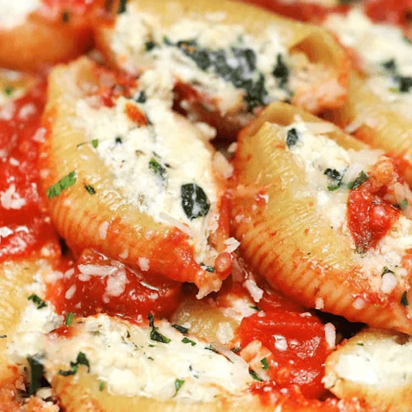 Close-up of baked stuffed pasta shells with ricotta, spinach, marinara sauce, and Parmesan cheese.